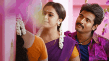 a man in a purple shirt stands next to a woman in a purple saree