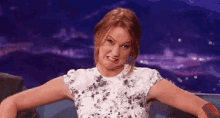 a woman is making a funny face while sitting in a chair with her arms outstretched .