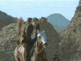 a man is riding a horse on a hillside