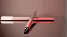 a red pen is laying on a black surface next to a white pen