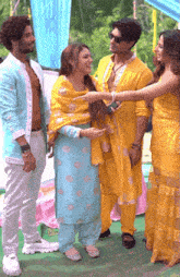 a group of people standing next to each other and one of them is wearing a yellow dress