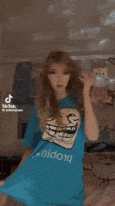 a woman wearing a blue t-shirt with a troll face on it .