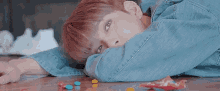 a young boy is laying on the floor with his head on his arms surrounded by candy .