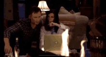 a man and a woman are looking at a laptop in a living room