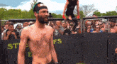 a shirtless man is standing in front of a fence that says ' stiffs ' on it