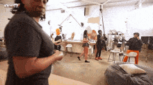 a man in a black shirt stands in a room with a sign that says now christ tv