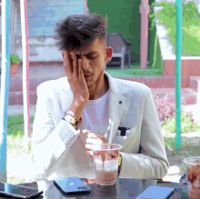 a man in a white jacket sits at a table with a cup of coffee