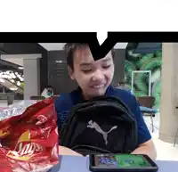 a boy sitting at a table with a bag of lays chips in front of him