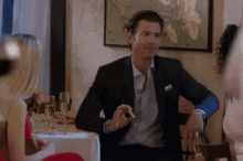 a man in a suit is sitting at a table with a woman in a red dress and wine glasses .