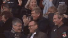 a group of people sitting in a stadium watching a soccer game with the score at 2-0
