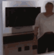 a blurry picture of a woman standing in front of a flat screen tv .