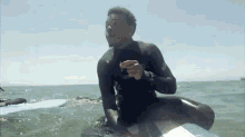 a man in a wetsuit is riding a surfboard in the ocean .