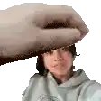 a woman is taking a selfie and a hand is holding her head .