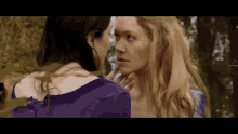 two women are looking at each other in the woods .