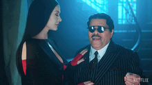 a man and a woman are standing next to each other and the man is wearing sunglasses and a netflix logo