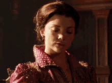 a woman in a red dress with pearls on the sleeves is looking down