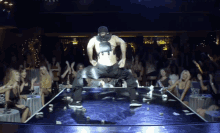 a man is kneeling down on a stage in front of a crowd of women
