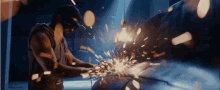 a man wearing a helmet is cutting a piece of metal with sparks coming out of his hands