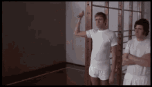 two men are standing next to each other in a gym . one of the men is flexing his arm .