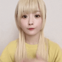 a girl with blonde hair is making a heart with her hands