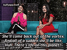 two women are sitting on a blue couch talking to each other and laughing .