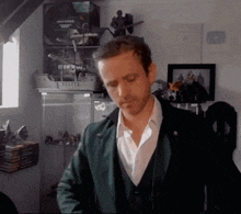 a man in a green jacket is standing in front of a display case that has a ship on it