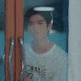 a man in a white shirt is standing in front of a window .