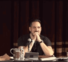 a man is sitting at a table with a microphone and a laptop