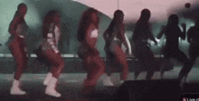 a group of women are dancing on a stage in front of a live audience