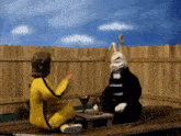 a man in a yellow suit is sitting next to a rabbit in a black suit