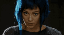 a woman with blue hair is making a serious face