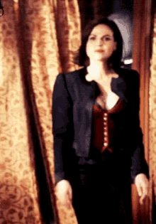 a woman in a black jacket and red vest is standing in front of a door .