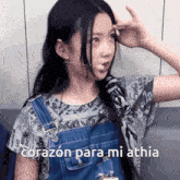a girl wearing overalls and a newspaper shirt says corazon para mi athia
