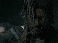 a man with long hair and a beard is covered in dirt