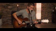 a man is playing an acoustic guitar in front of a microphone