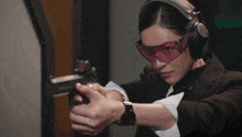 a woman wearing headphones and glasses is holding a gun