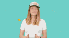 a woman wearing a white shirt and a hat applauds with her arms outstretched ..