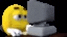 a pixel art of a yellow smiley face sitting in front of a computer .