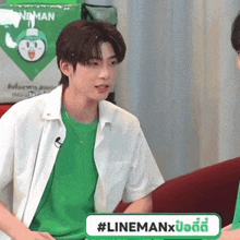 a man in a green shirt is sitting in front of a sign that says #linemanx