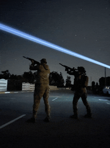 two soldiers are standing in a parking lot with their guns pointed at each other
