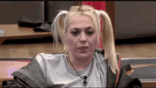a woman with pigtails and a necklace is sitting at a table with her eyes closed .
