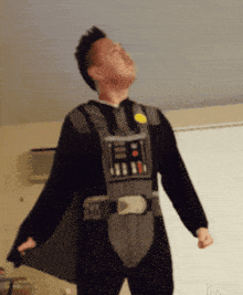 a man in a darth vader costume is standing in a room with his arms outstretched