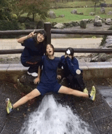 a girl in a blue shirt is sitting on a rock with her legs outstretched