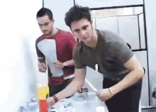 a man standing next to another man with a box of vitamin c on the table