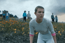 a group of people standing in a field of flowers including a girl with short hair