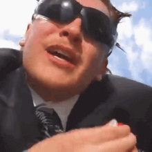 a man in a suit and tie is wearing sunglasses and a life vest