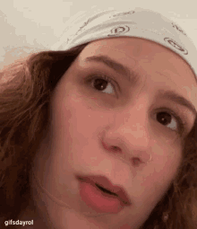 a close up of a woman wearing a bandana on her head and making a funny face .