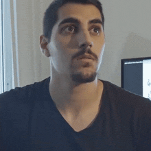a man with a beard wearing a black shirt is looking at something