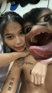 a man with a tattoo on his arm has his tongue out and a woman holds his neck