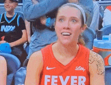 a female basketball player is wearing a red jersey that says fever